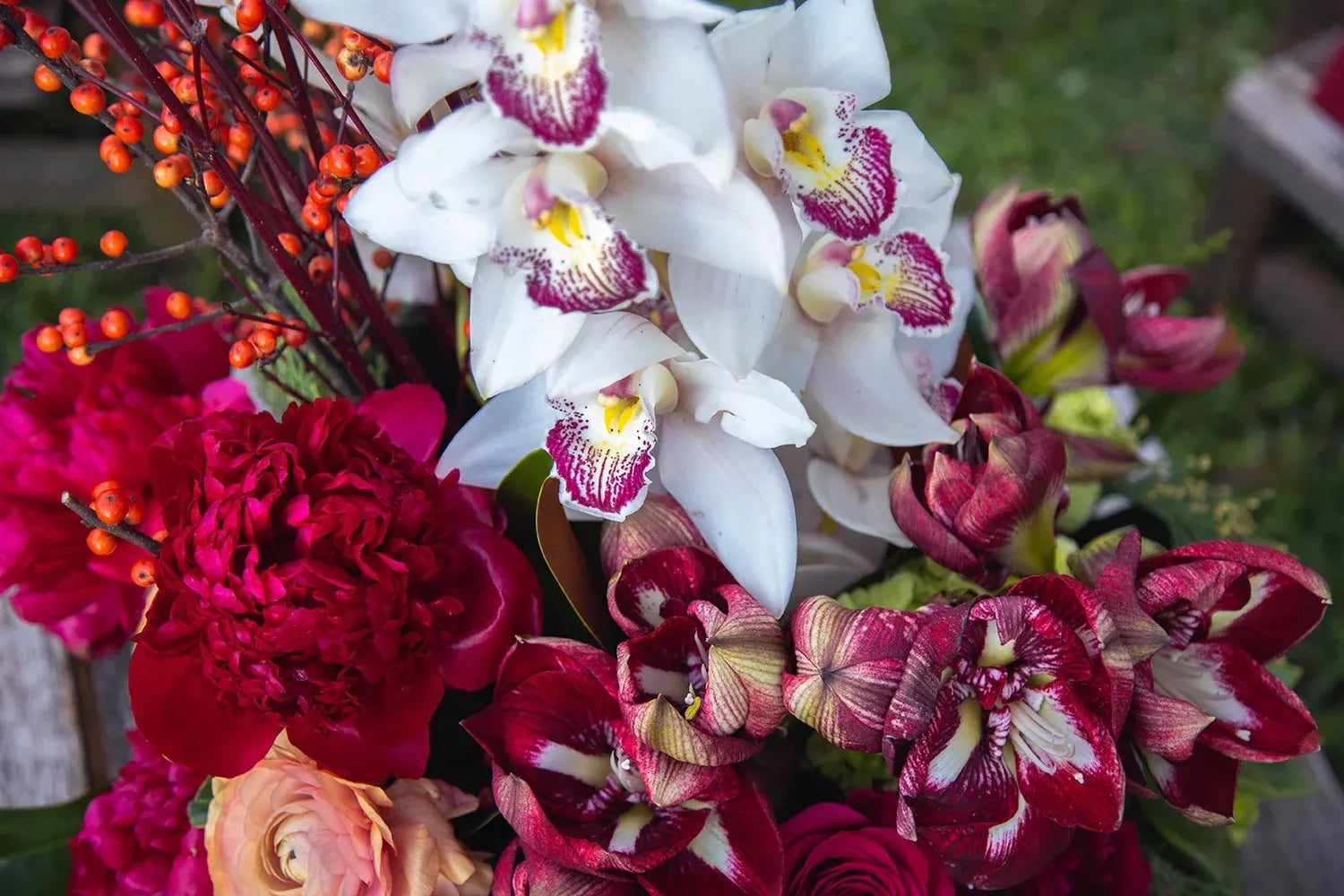 Vibrant floral arrangement featuring white orchids, red peonies, and burgundy blooms for a stunning decorative touch.