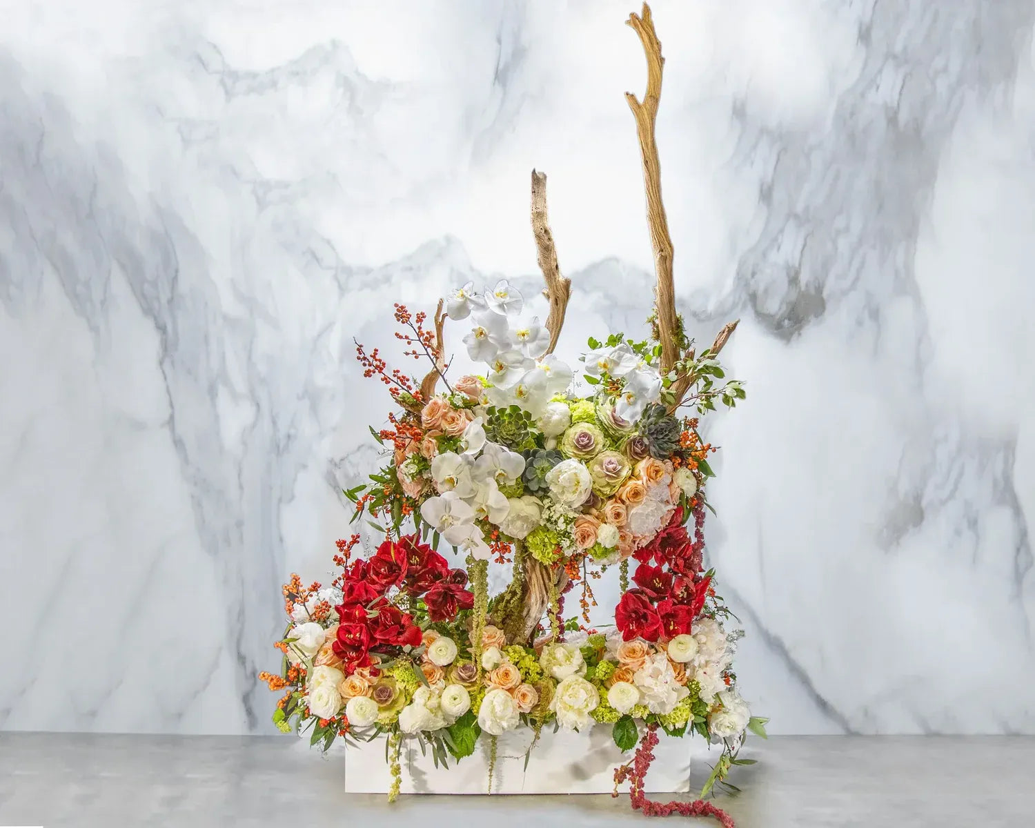 A stunning arrangement of vibrant roses, orchids, and greenery artfully displayed in a modern design on a marble backdrop.