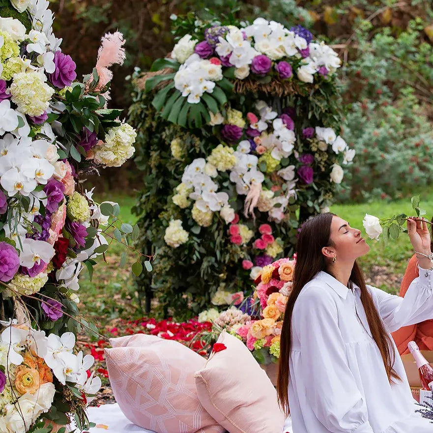A serene moment featuring a woman amidst vibrant floral arrangements at a cheerful outdoor setting.