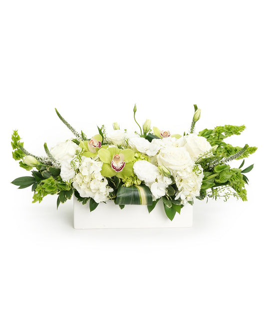 Elegant white floral arrangement featuring roses, orchids, and hydrangeas in a sleek white box.