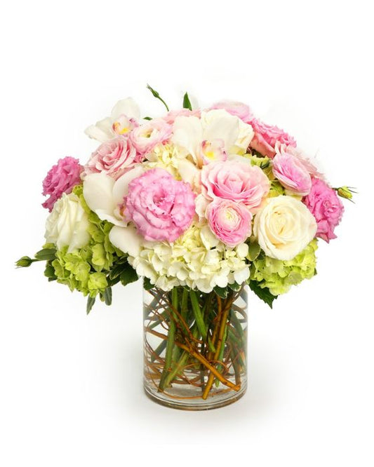 Beautiful floral arrangement featuring pink roses, white orchids, and green hydrangeas in a glass vase.