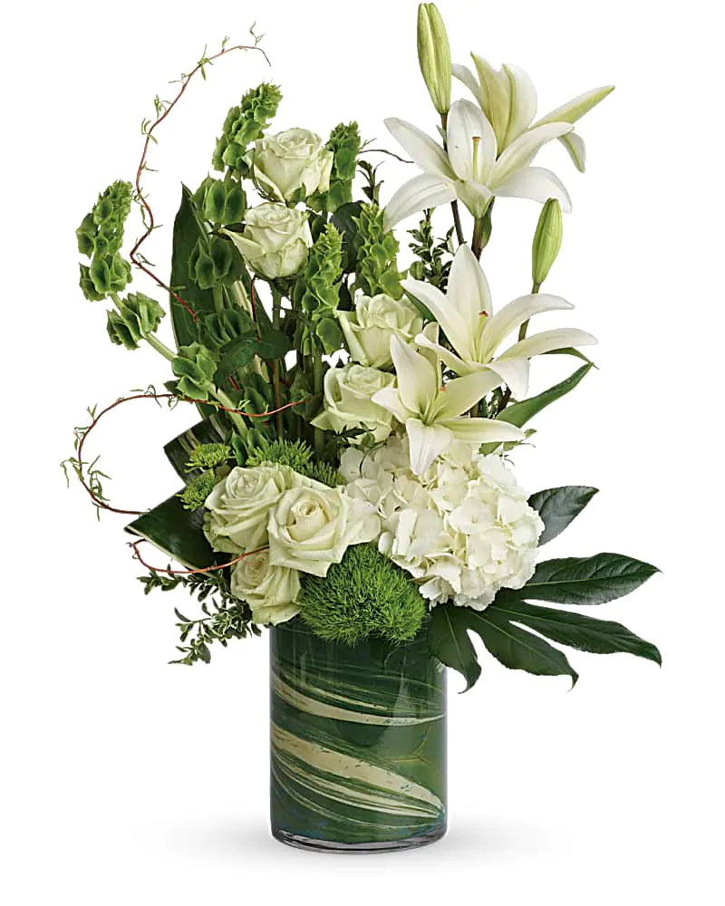 Elegant white flower arrangement with lilies, roses, hydrangeas, and greenery in a stylish marble vase.