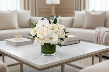 Flower arrangement of white Orchids and roses on a white marble coffee table, living room background