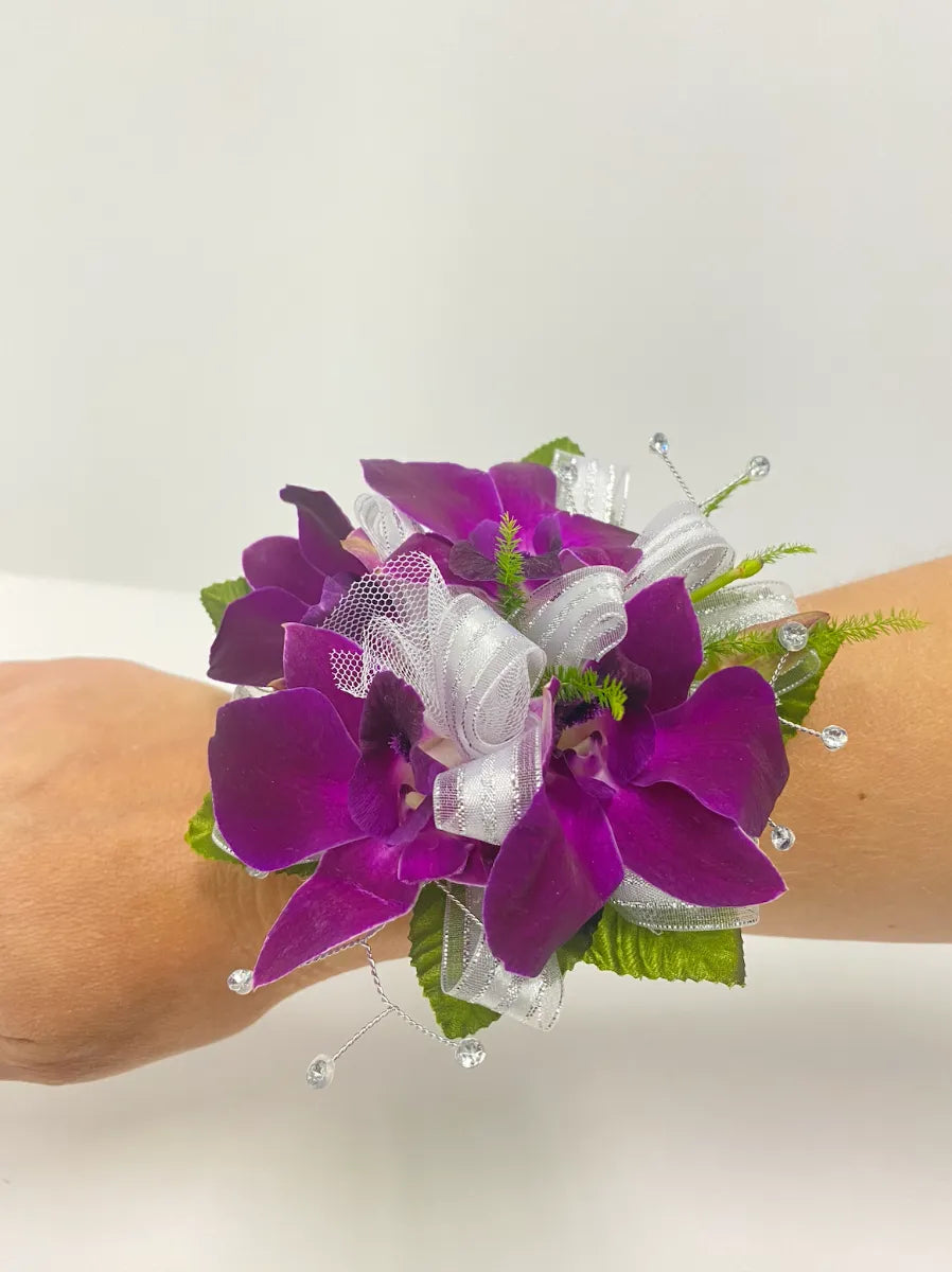 Beautiful purple orchid corsage with delicate ribbons and sparkling embellishments, perfect for special occasions.