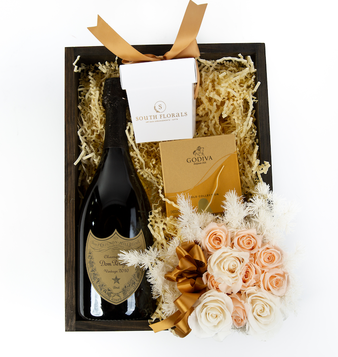 Elegant gift box featuring vintage Dom Pérignon, gourmet Godiva chocolates, and delicate floral arrangement.
