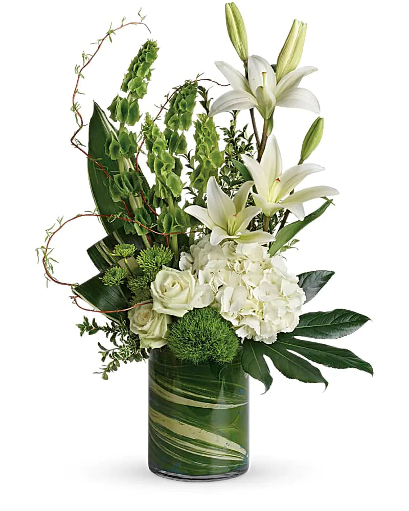 Elegant arrangement of white lilies, roses, and green accents in a stylish glass vase. Perfect for any occasion.